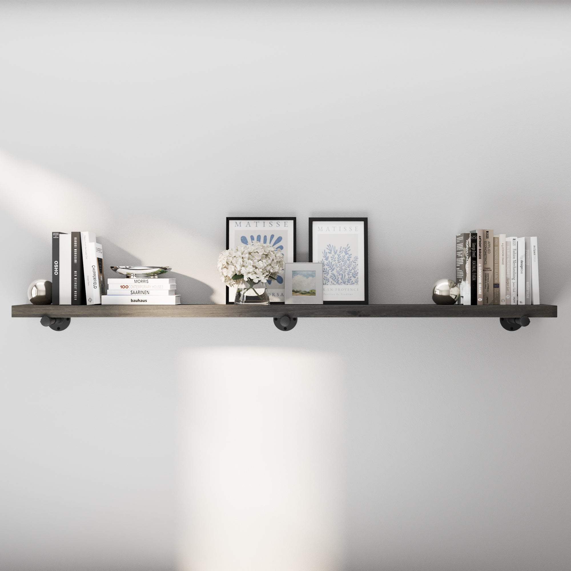 72 inch industrial pipe shelf in a rich ebony finish, styled with books, framed art, and décor for a sleek modern farmhouse look. This extra long wall shelf adds stylish storage to living rooms, offices, bedrooms, or dining spaces.