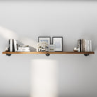 72 inch extra long industrial pipe shelf in a warm provincial finish, styled with books, framed art, and decorative accents. This extra long wall shelf blends rustic farmhouse charm with industrial décor for living rooms, offices, or bedrooms