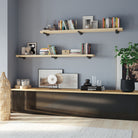 Styled living room display featuring 72 inch long floating shelves with black pipe brackets with a natural unfinished wood finish. These long floating shelves add open wall storage for books, plants, and decorative organization in modern or rustic spaces.