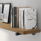 A 72” long floating book shelf featuring a rich golden oak finish with visible wood grain. A long wall-mounted bookshelf with sturdy black pipe brackets, ideal for farmhouse, modern, or industrial décor.