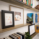 Close-up of a plant shelf showcasing a mix of framed photos, books, and small decorative pieces.