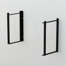 Two black rectangular shelf brackets mounted on a wall without shelves.
