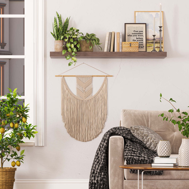 The wood shelf walnut color stylishly holds books, candles, and plants, adding a touch of nature and tranquility beside a cozy, draped armchair.