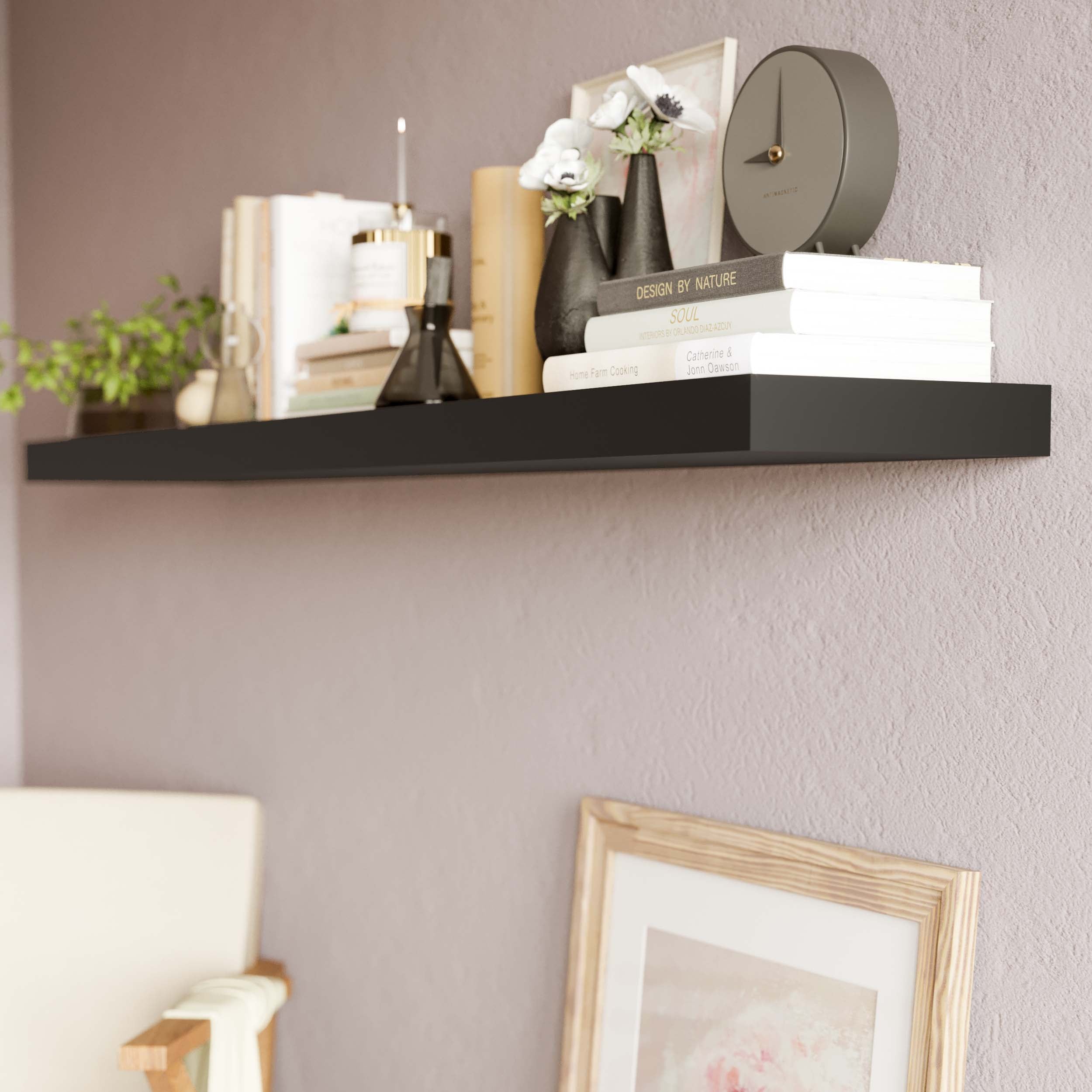 Black hanging shel in a cozy setting, adorned with books, vases, and a modern clock, adding a touch of sophistication.