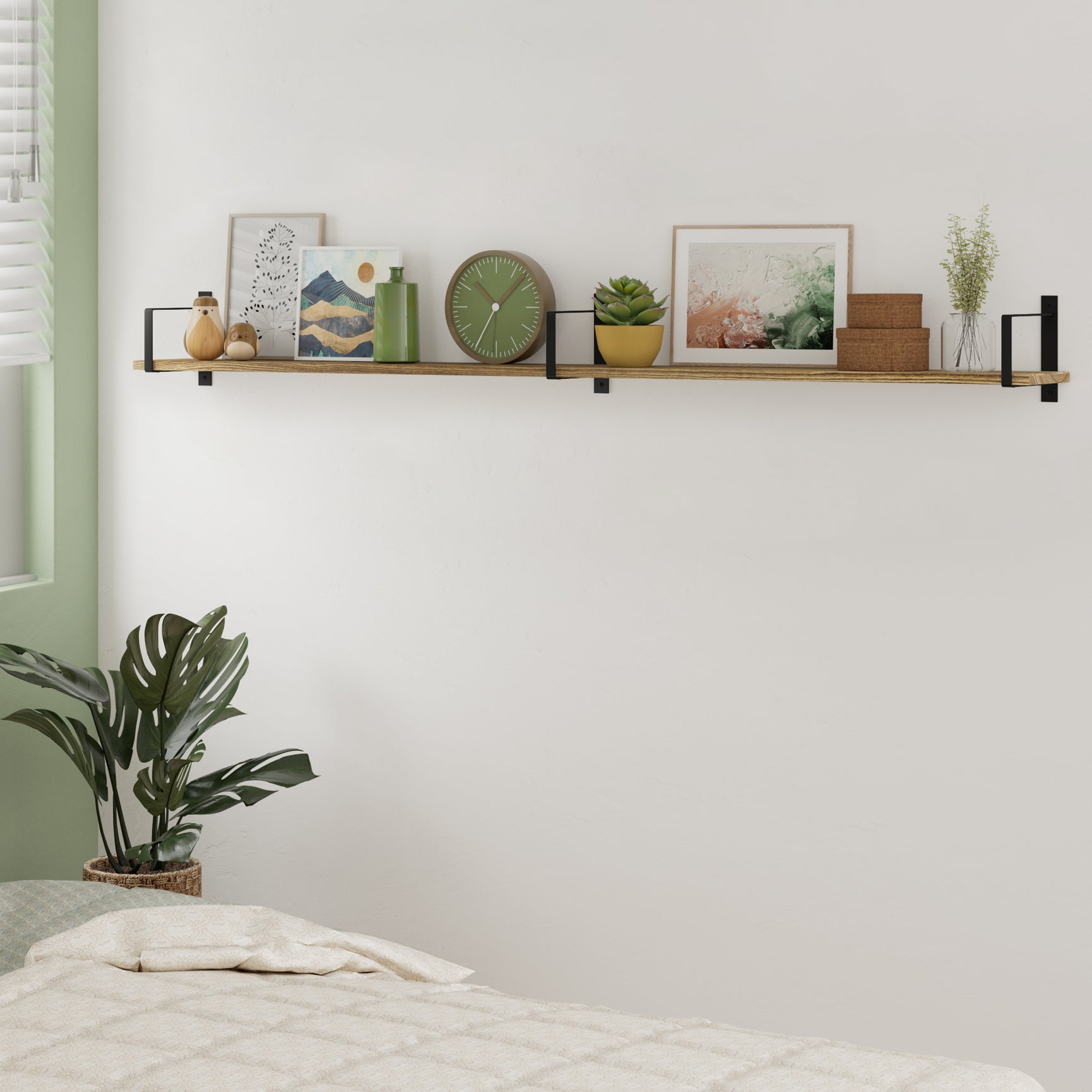 Styled long floating shelf burnt in a bedroom setting, decorated with art and plants.