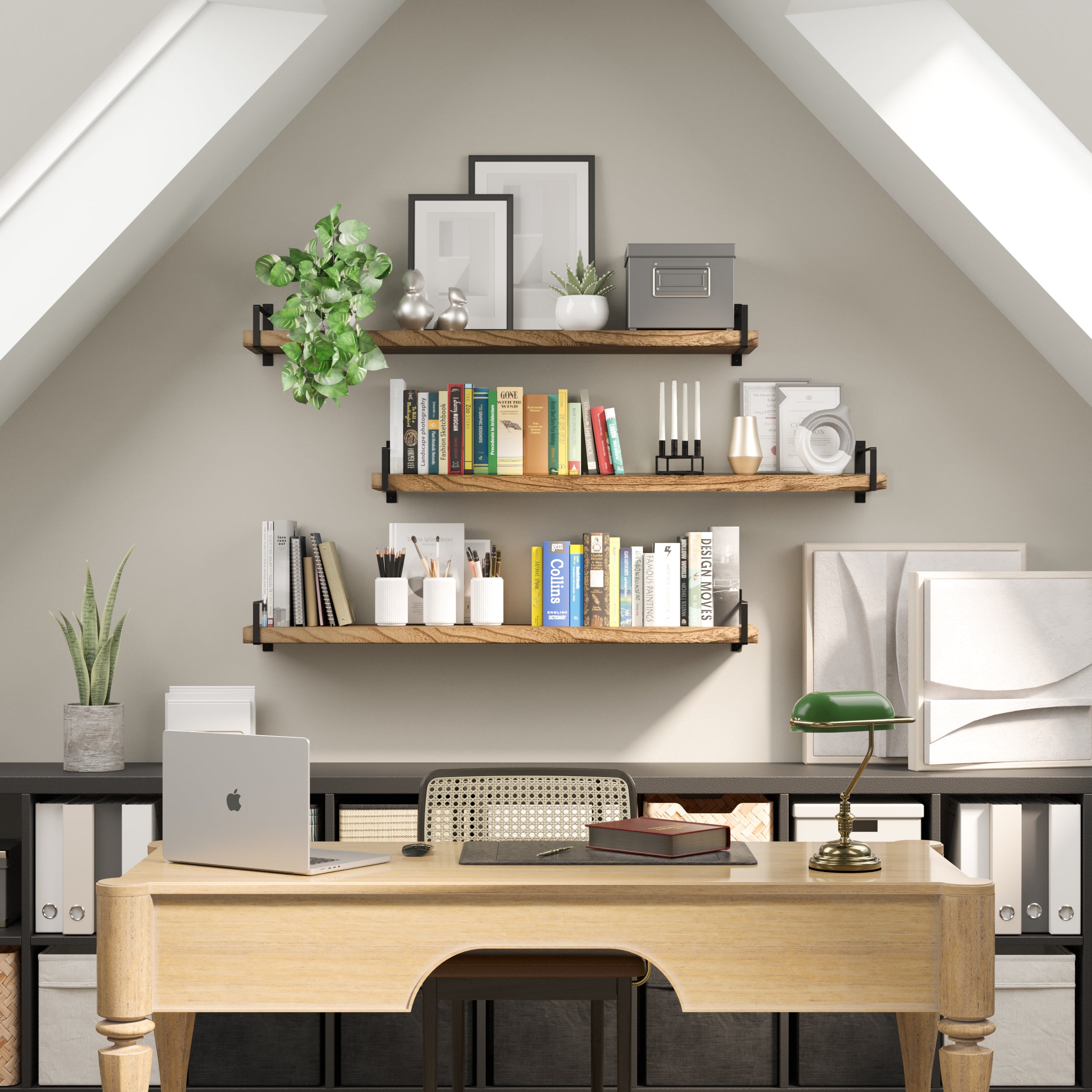 A cozy attic office with three wood office shelves mounted on a sloped ceiling. Decorated with books, plants, and frames, the space is thoughtfully styled for productivity and visual warmth.