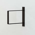 Black rectangular wood shelf bracket mounted on a wall without a shelf.
