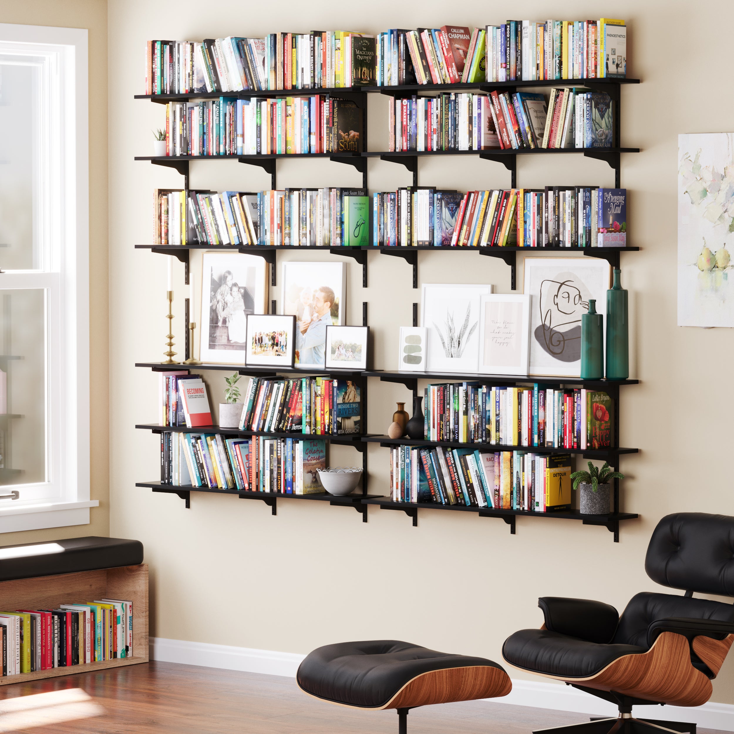 A cozy reading area with black floating shelves on a wall full of colorfully spined books and personal decor items.