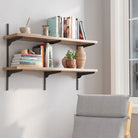 2 tiered farmhouse shelves with books and decor items against a white wall, with a chair in the foreground.
