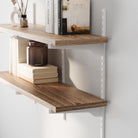 Real wood shelves with adjustable white brackets with decorative items against a white wall