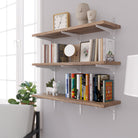 Floating wall book shelves with books and decorative items against a white wall.