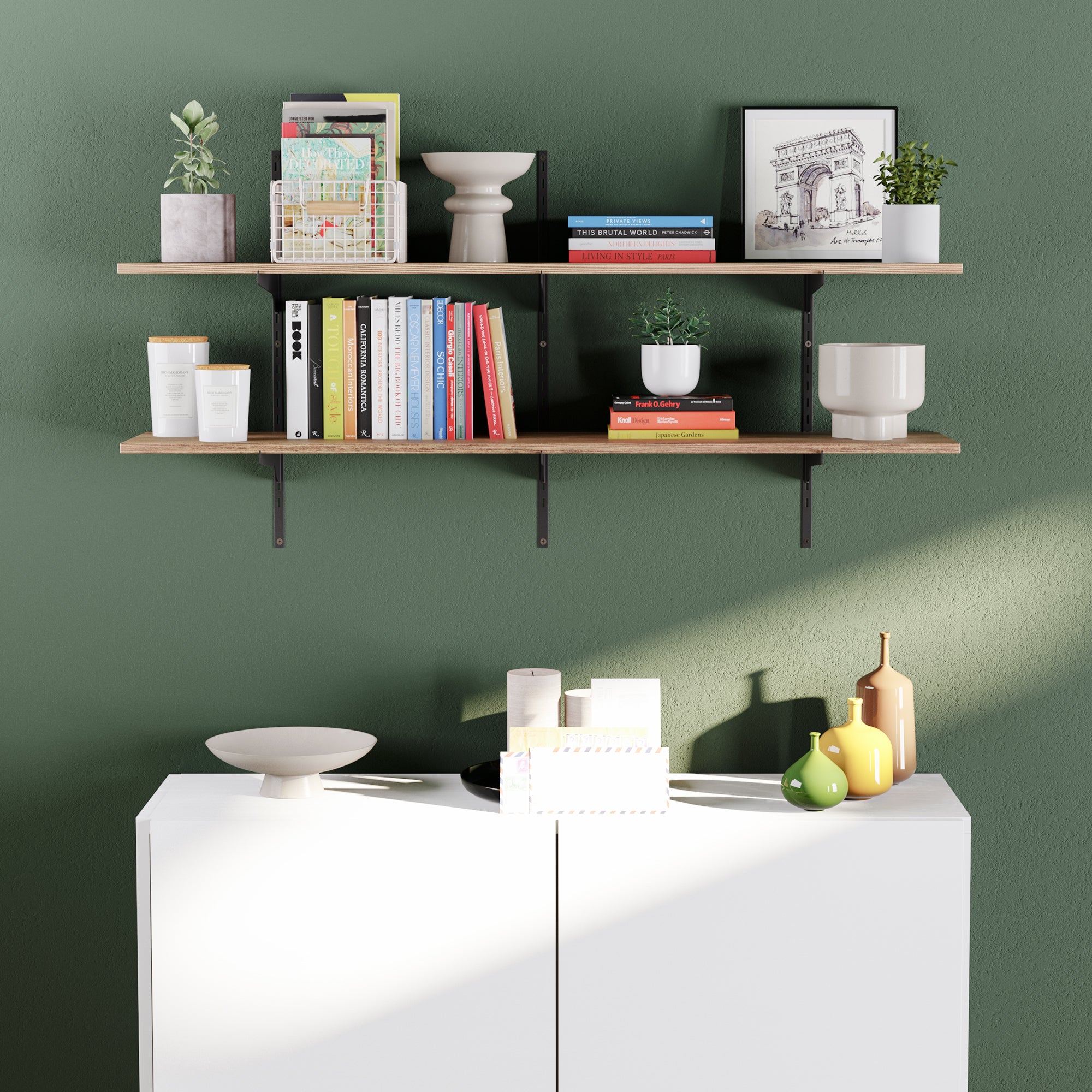 A rustic shelving unit with adjustable bracket holding books, plants, and decorative items against a green wall.