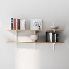 2 tiered wooden wall bookshelves with books and decorative items against a gray wall
