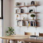 Rustic shelving unit suitable for boho and farmhouse decor with books and decor items above a wooden dining table.