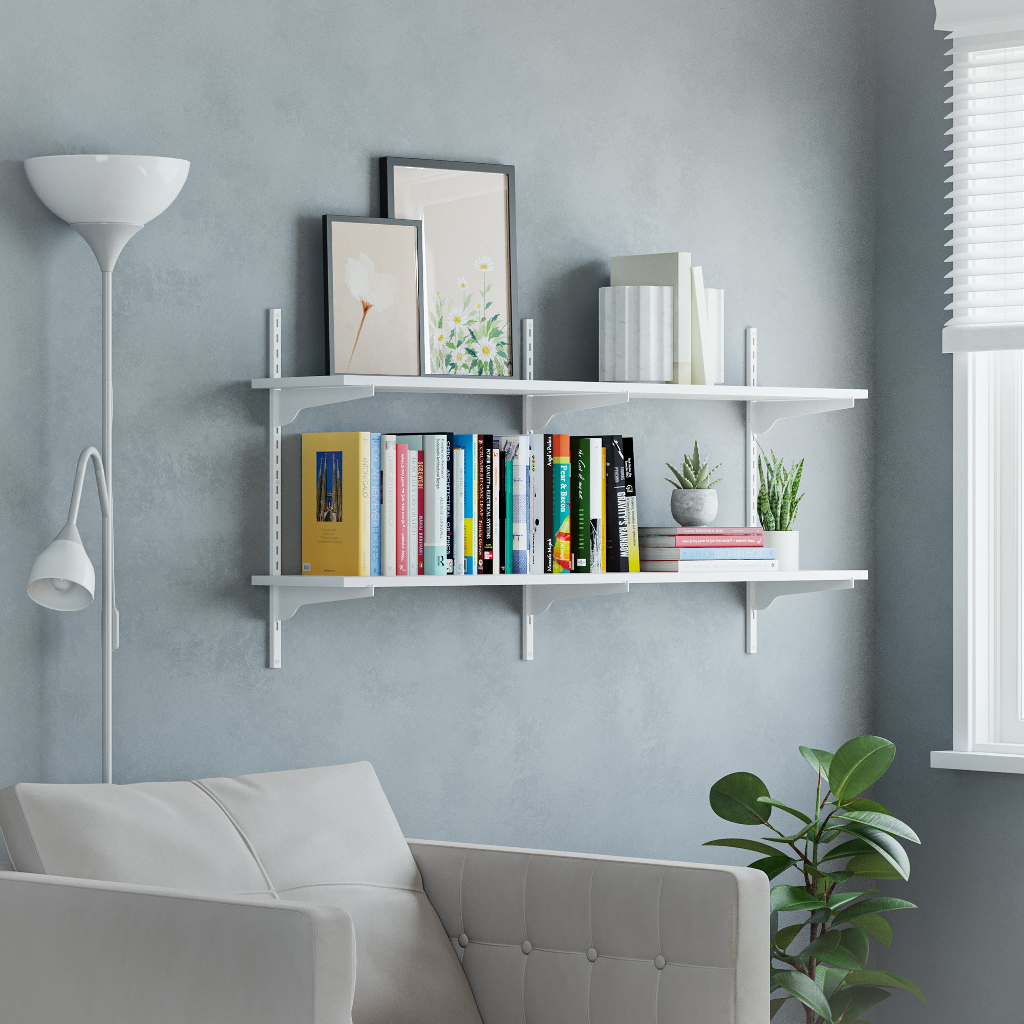 White floating wall bookshelves with white adjustable brackets with books, plants, and decor against a gray wall.