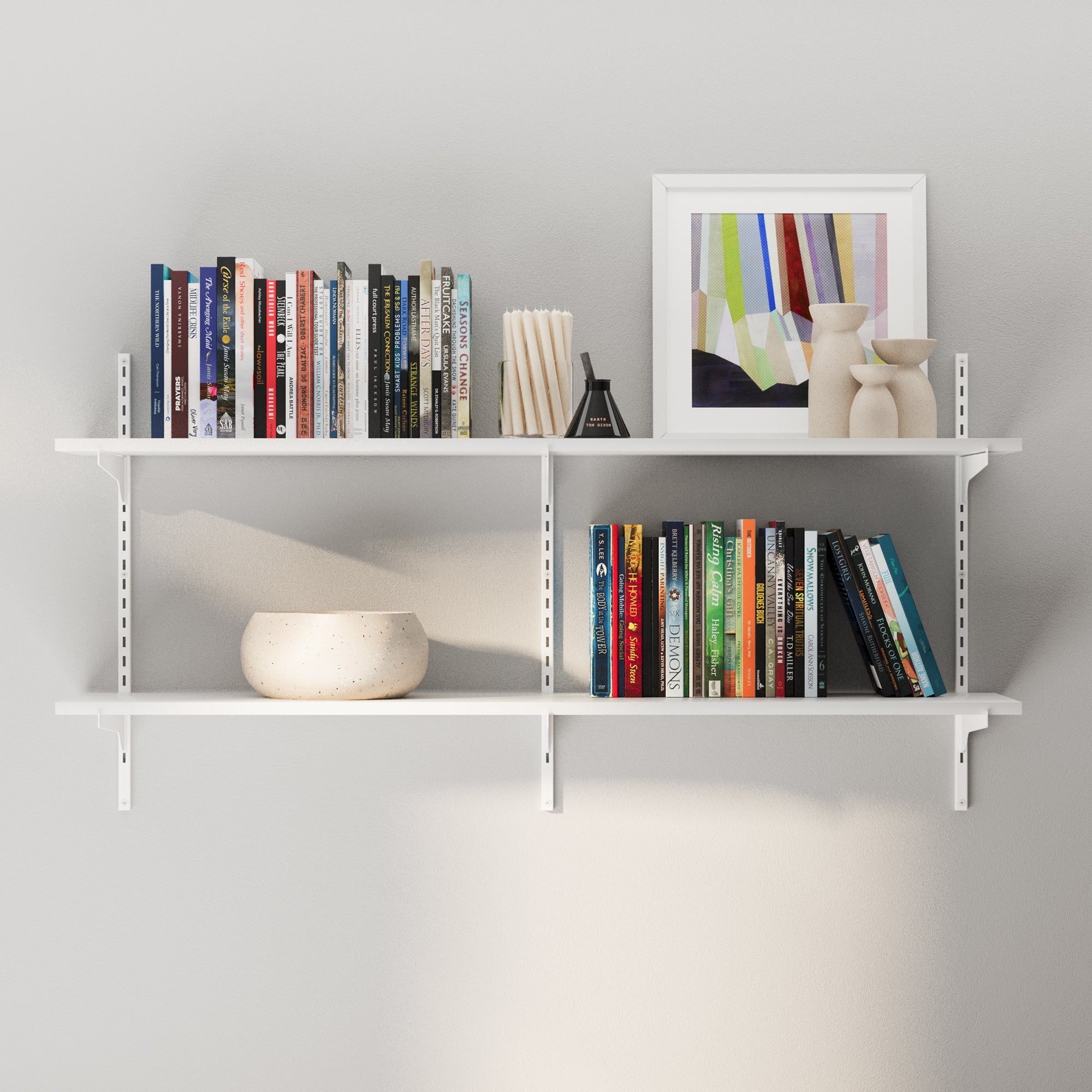 White wall-mounted adjustable shelf with 2 tiers with books and decorative items against a gray wall