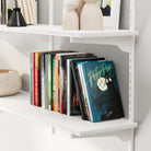 Children's books on a white adjustable shelf with decorative vases.