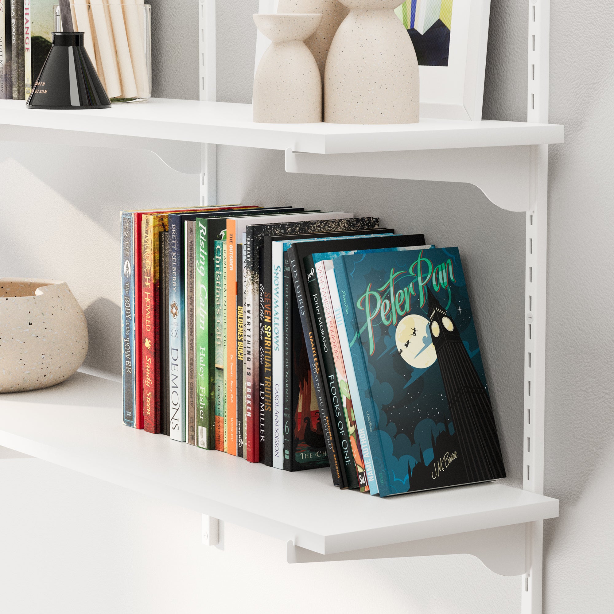 Children's books on a white adjustable shelf with decorative vases.