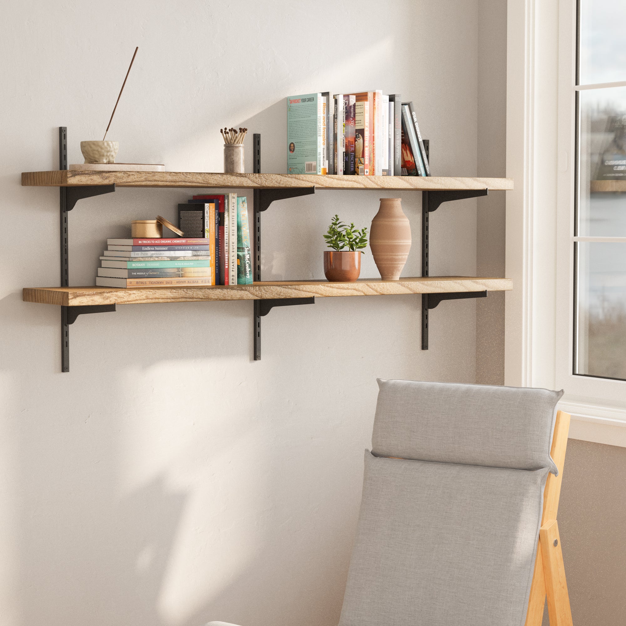 54 inch long floating bookshelf with black adjustable brackets with books and plants in a room with a chair and window.