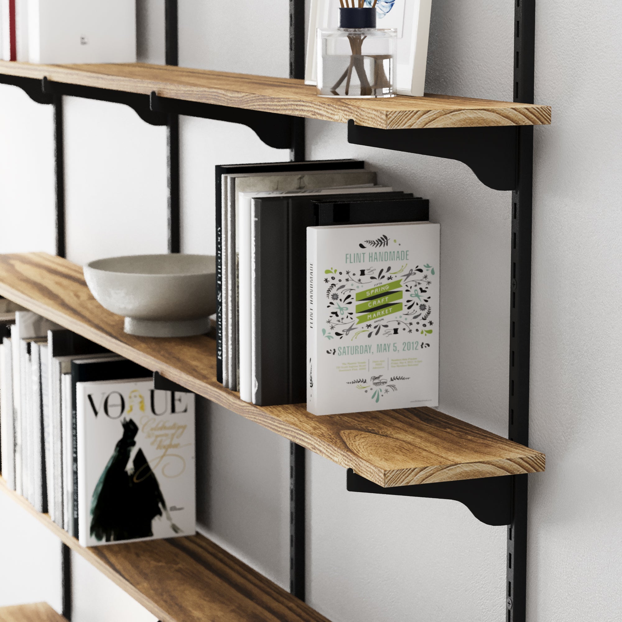 Long hanging shelves with black adjustable brackets and rails holding books and decorative items against a white wall
