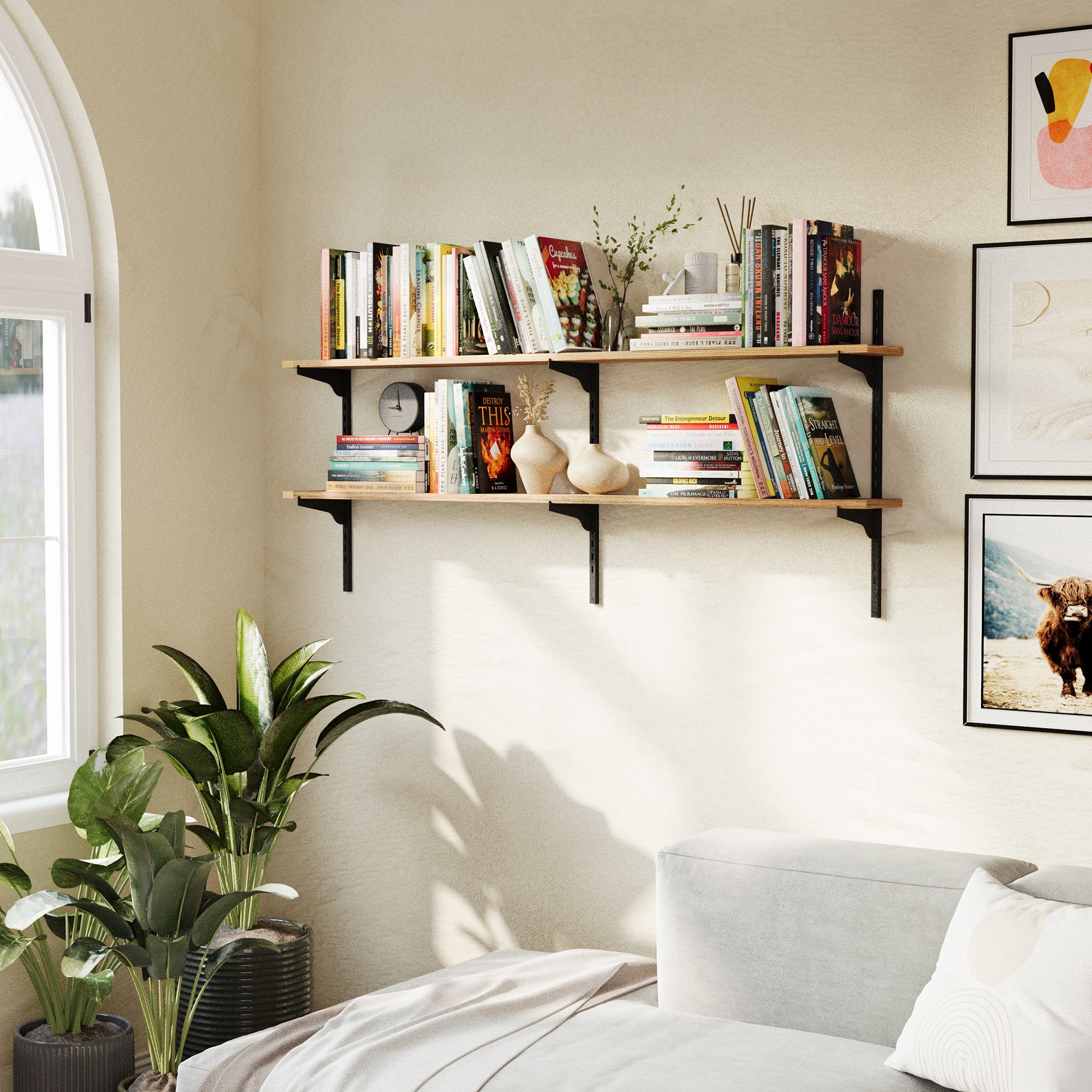 Living room shelves with books and decor in a room with a bed and framed pictures.