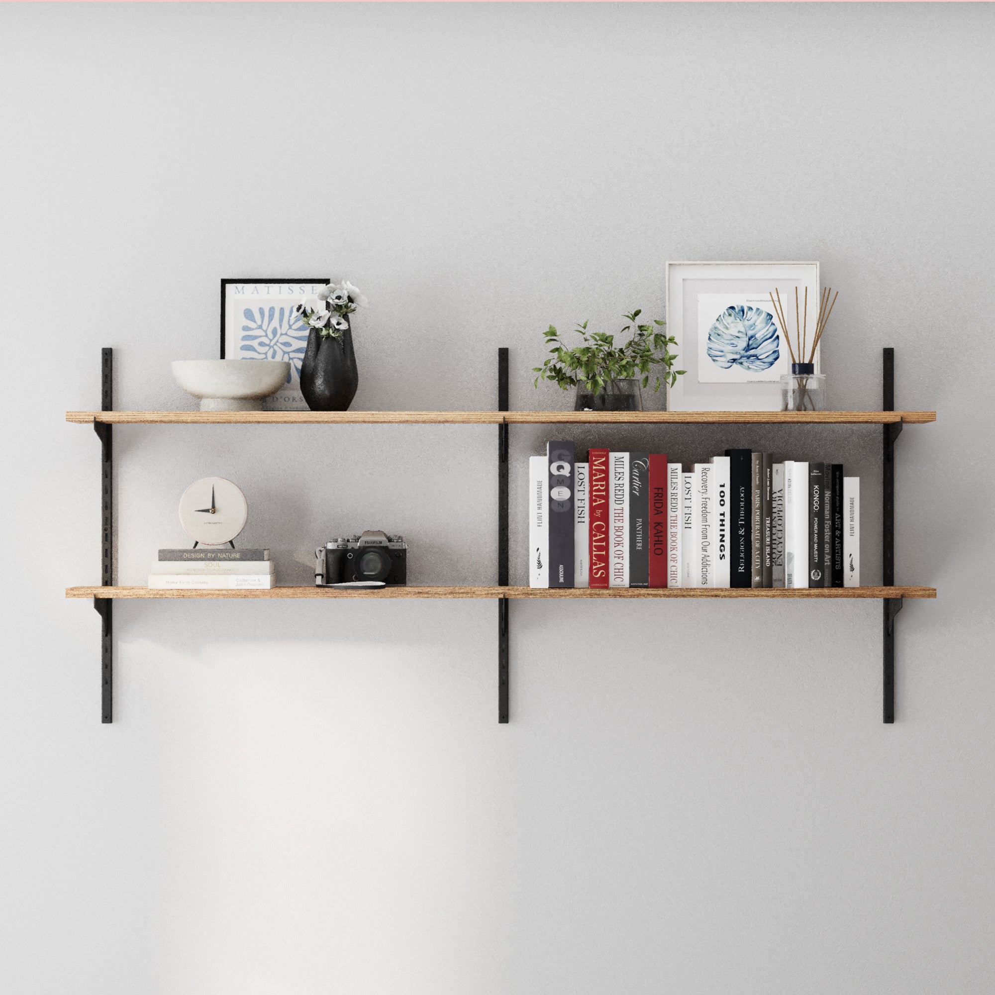 2 tier decorative shelves with books, decor items, and plants against a gray wall.
