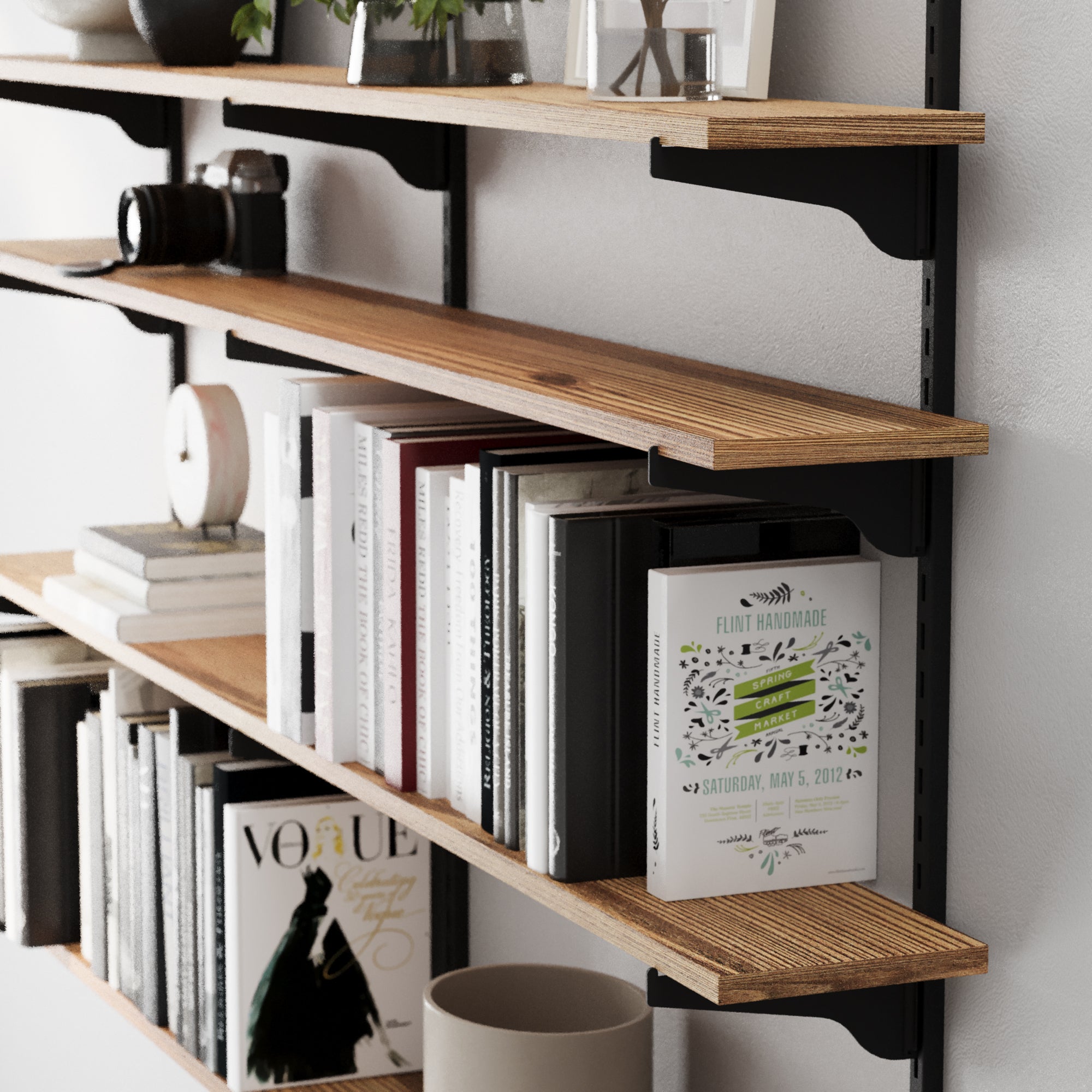 Storage shelving system with adjustable brackets holding books and decor items against a white wall