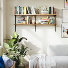 Living room setup with wall bookshelf, plant, and sofa