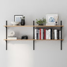 A floating bookshelf unit in a rich burnt finish with books, decorative items, and plants against a gray wall