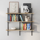 Three-tier wall-mounted adjustable shelf with black metal rails and natural wood boards, styled with books, ceramics, and decor for a clean, modern aesthetic.