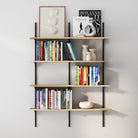 Four-tier adjustable wall bookshelf with black metal rails and light wood boards, decorated with books, ceramics, and artwork for a clean and modern look.