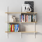 Wall-mounted bookshelf with books and decorative items against a light gray wall