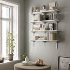 White wall shelves with decorative items against a gray wall in a room with a window.