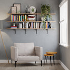 Modern living room with a gray sofa, 72 inch long and 3 tier living room shelving system, books, and plants against a gray wall.