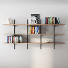 3 tier wooden shelves with books and decor items against a white wall