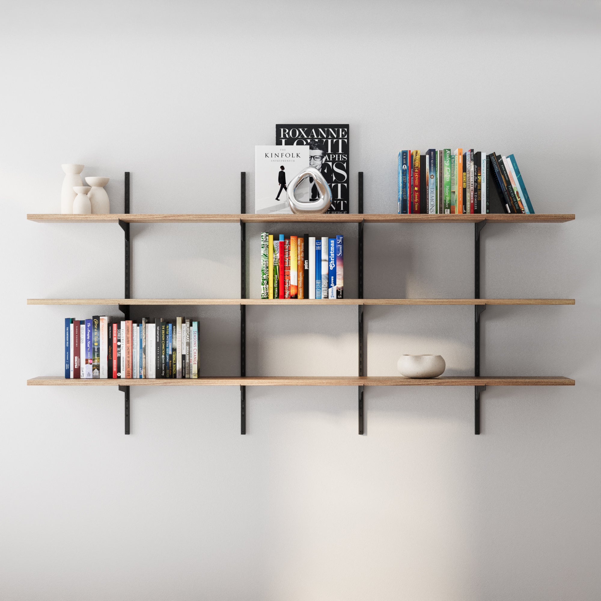 3 tier wooden shelves with books and decor items against a white wall