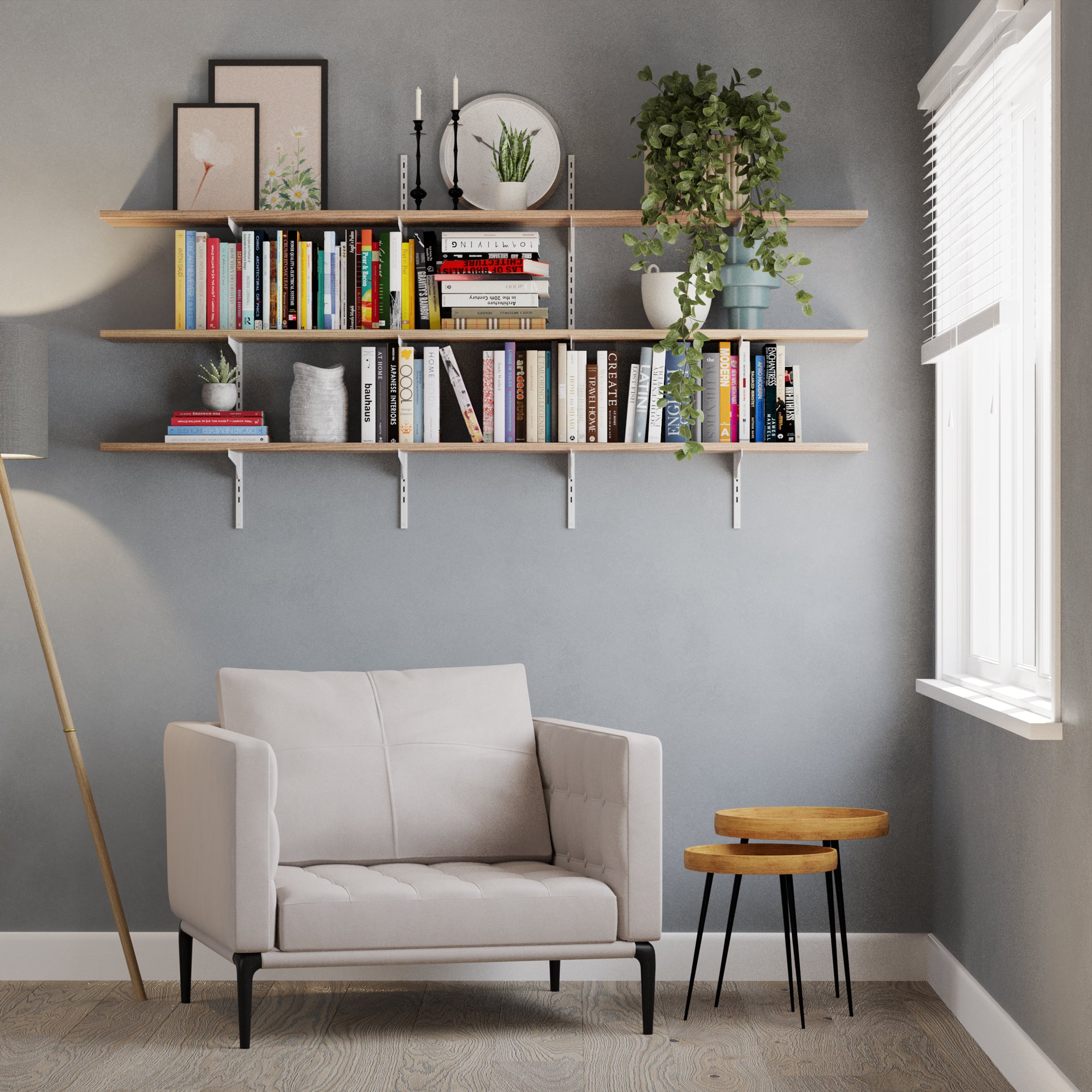 Modern living room with a gray sofa, decorative 3 tiered shelves, books, and plants against a gray wall.