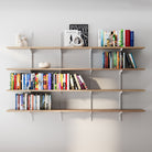 4 tier wall mounted shelving unit with books and decor against a white wall