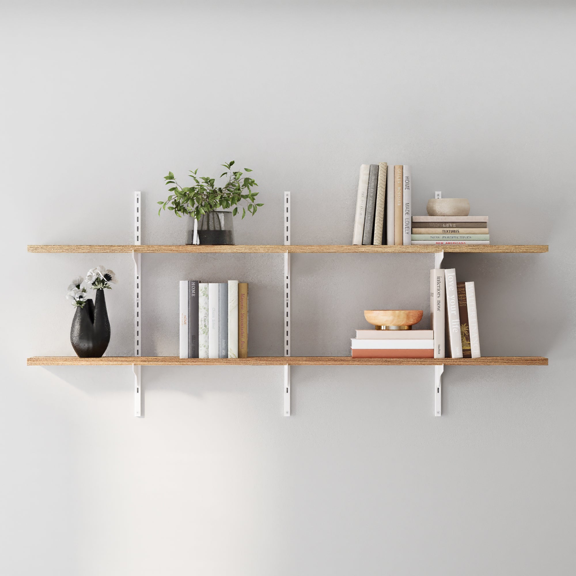 Two-tier wall-mounted shelf with white metal rails and brackets, featuring light wood boards styled with books, plants, and minimal decor for a clean, Scandinavian-inspired look.