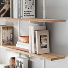 4 tiered floating shelving unit with books and decorative items against a white wall