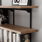 Hanging shelves for wall with books and framed pictures on a gray wall.