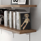 Rustic shelf with books and a framed picture on a white wall.