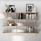 60 inch long floating shelving unit for wall with books, decorative items, and framed pictures against a white wall.