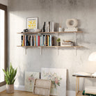 60 inch long floating book shelving unit  with books and decor items against a concrete wall.