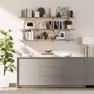 Modern living room with 3 tiered living room storage shelving unit, books, and decor items against a white wall.
