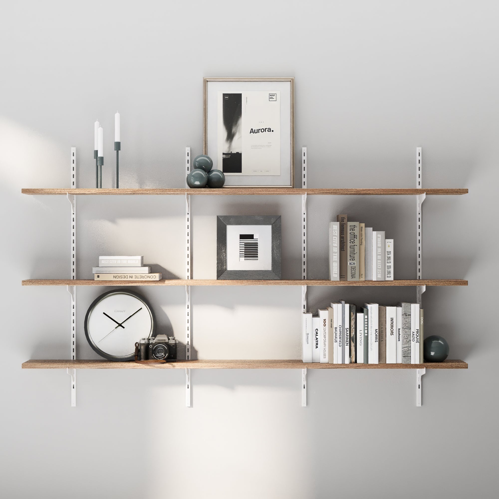 3 tiered long floating shelf with books, a clock, and decorative items against a gray wall.