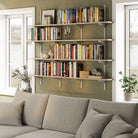 Rustic shelving unit for living room decor with books and decor items above a gray sofa in a living room.