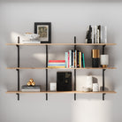 3 tier wood wall shelving unit with books and decor against a gray wall