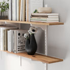 wooden shelf with white metal bracket, featuring stacked books, a wooden bowl, and a black vase, highlighting material texture and sturdy support.