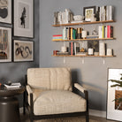 Stylish living room setup with three-tier shelves for living room decor above a chair, filled with books and décor, blending warm tones and modern interior design.